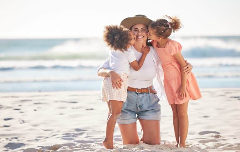 Portuguese Nationality for Children of Portuguese Citizens: Mom, kiss or children bonding on beach in Portugal in trust, security or love hug. Smile, happy or