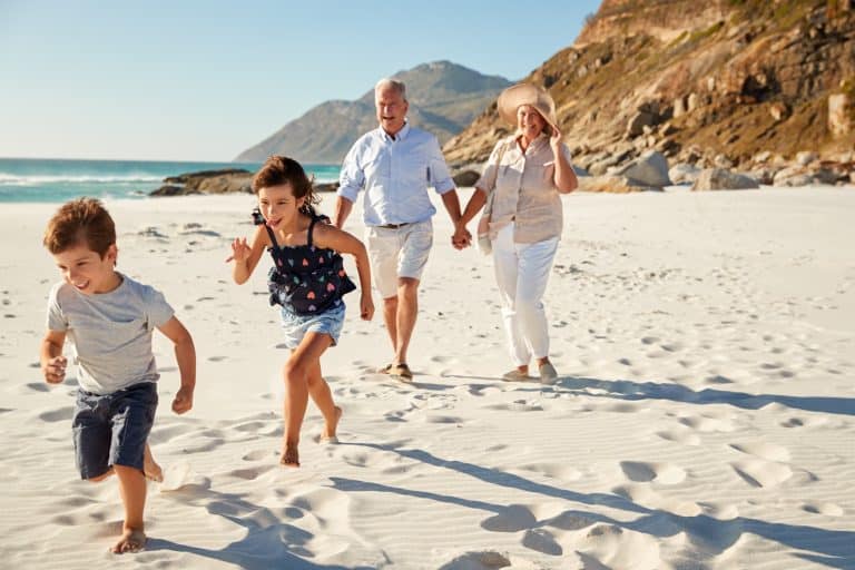 Portuguese Nationality for Great-Grandchildren: Senior white couple and their grandchildren walking on a sunny beach, close up